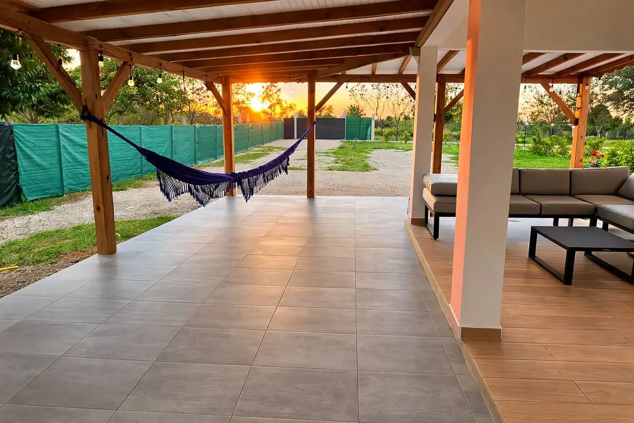 Terrasse couverte au coucher du soleil, hamac et salon de jardin
